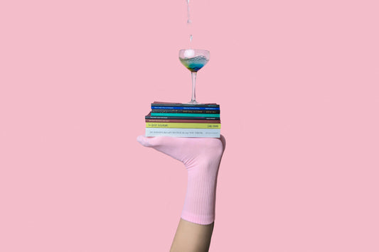 balancing empathy and objectivity. Image shows a foot with bottom facing up balancing books and wine glass